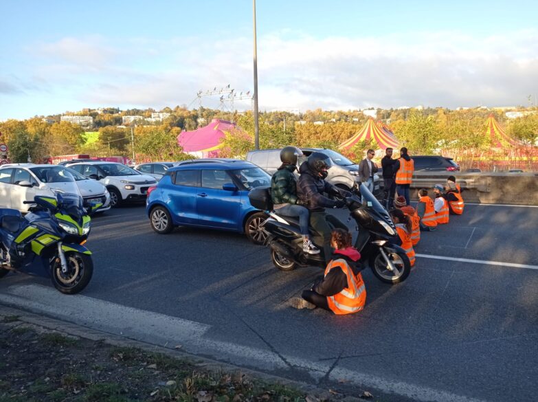 une moto passe entre deux personnes assises par terre